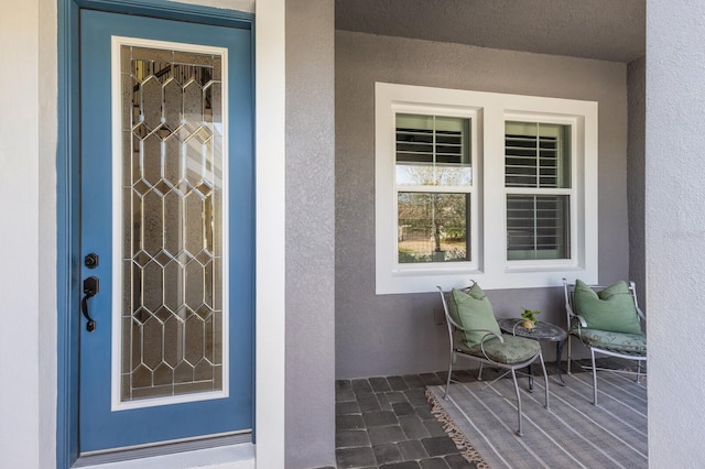 view of exterior entry with a porch and stucco siding