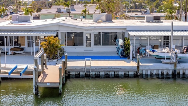 back of house with central AC, a water view, and boat lift