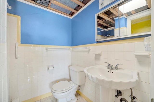 bathroom featuring wainscoting, tile patterned flooring, toilet, and tile walls