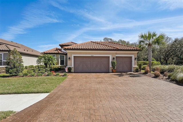 mediterranean / spanish-style house with a garage, decorative driveway, a tile roof, and stucco siding