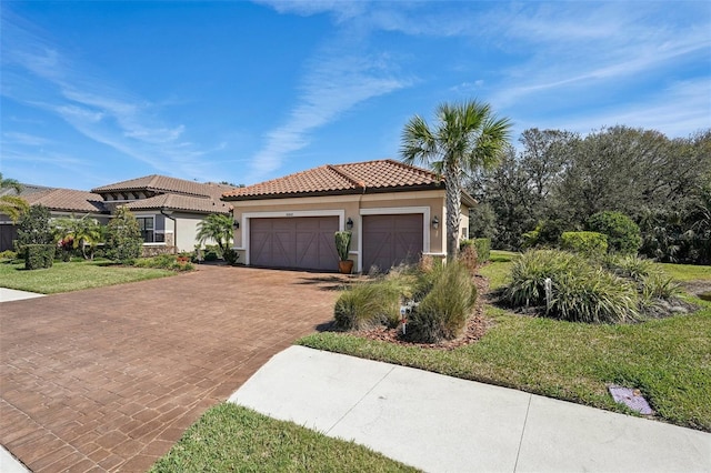 mediterranean / spanish home featuring a garage, stucco siding, a tile roof, decorative driveway, and a front yard