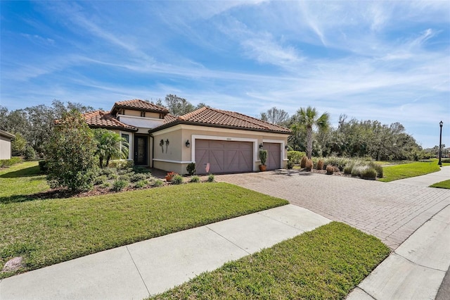 mediterranean / spanish-style house featuring a garage, stucco siding, a tile roof, decorative driveway, and a front yard