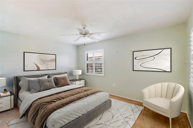 bedroom with light carpet, ceiling fan, and baseboards