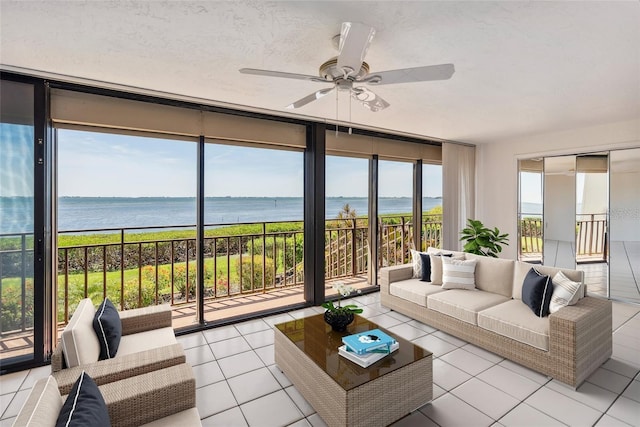 sunroom / solarium featuring a water view and ceiling fan