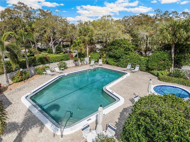 community pool with a patio area and fence