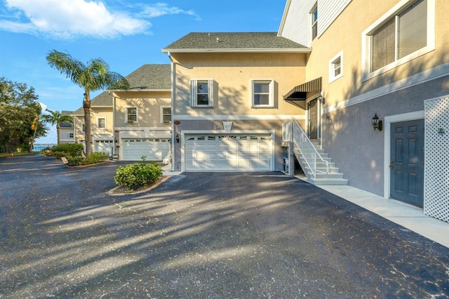 exterior space with a garage, aphalt driveway, and stucco siding