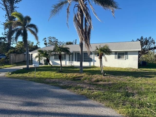 view of front of home with driveway, a front yard, fence, and stucco siding