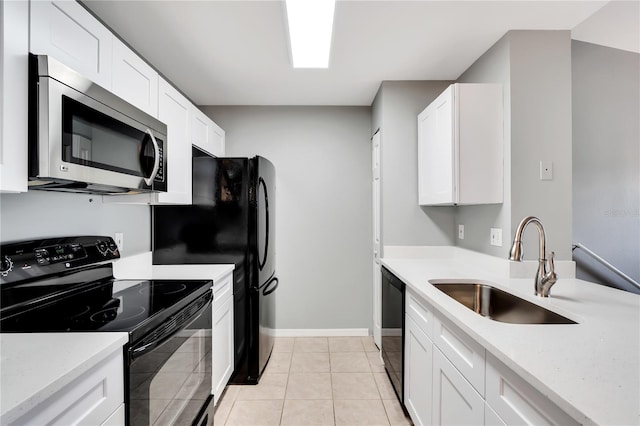 kitchen with light tile patterned floors, a sink, white cabinetry, baseboards, and black appliances