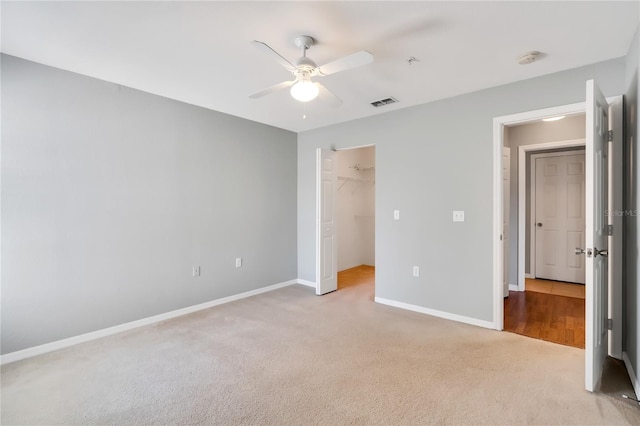 unfurnished bedroom with light carpet, a spacious closet, visible vents, and baseboards