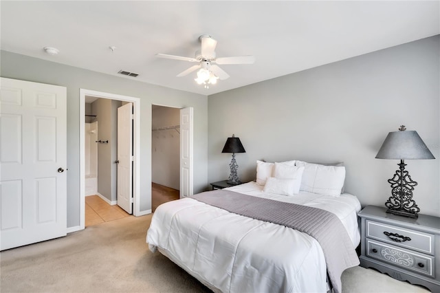 bedroom featuring a walk in closet, a closet, visible vents, a ceiling fan, and light carpet