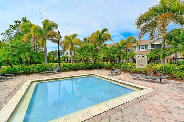 community pool with a patio area and fence