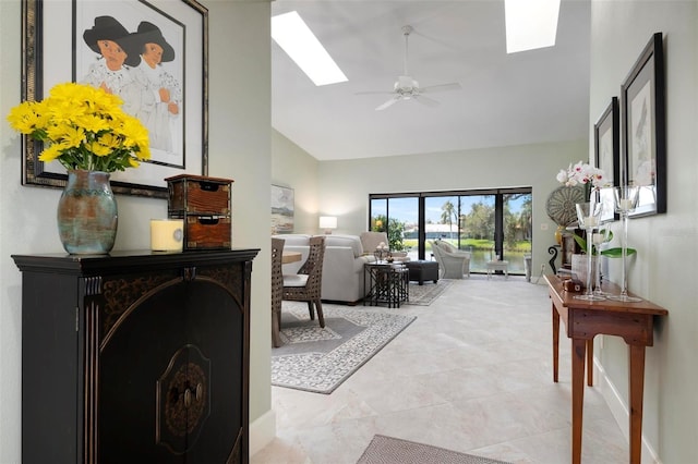 living room featuring ceiling fan, high vaulted ceiling, and a skylight