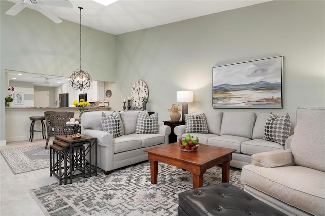 living area with high vaulted ceiling and ceiling fan with notable chandelier