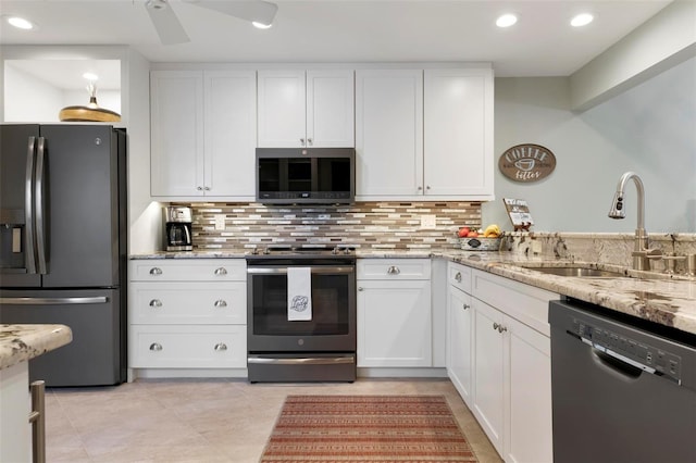 kitchen with stainless steel appliances, white cabinets, a sink, and light stone countertops