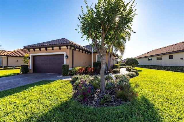 mediterranean / spanish house with decorative driveway, stucco siding, an attached garage, a tiled roof, and a front lawn