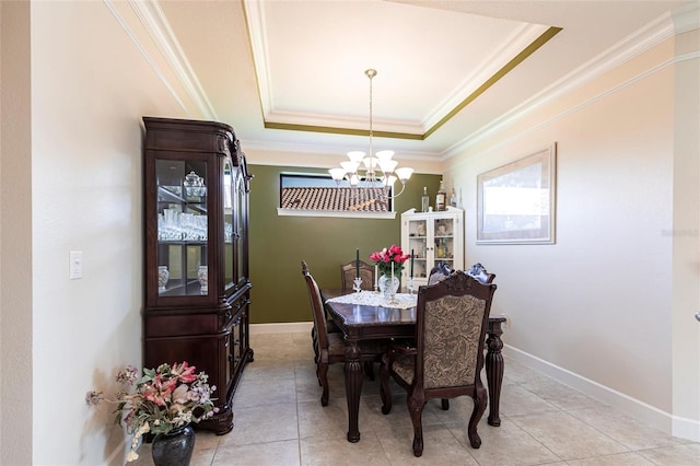 dining area with light tile patterned floors, baseboards, ornamental molding, a tray ceiling, and a chandelier