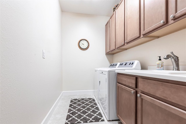 laundry room with a sink, washing machine and clothes dryer, cabinet space, and baseboards