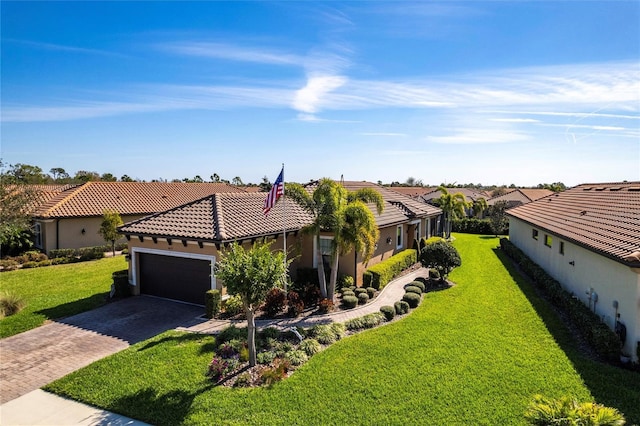 mediterranean / spanish-style house featuring a garage, a tiled roof, decorative driveway, a front lawn, and stucco siding