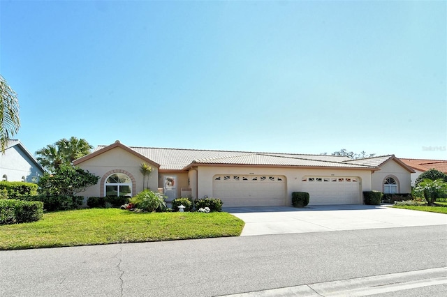 ranch-style house featuring concrete driveway, a tile roof, a front lawn, and stucco siding