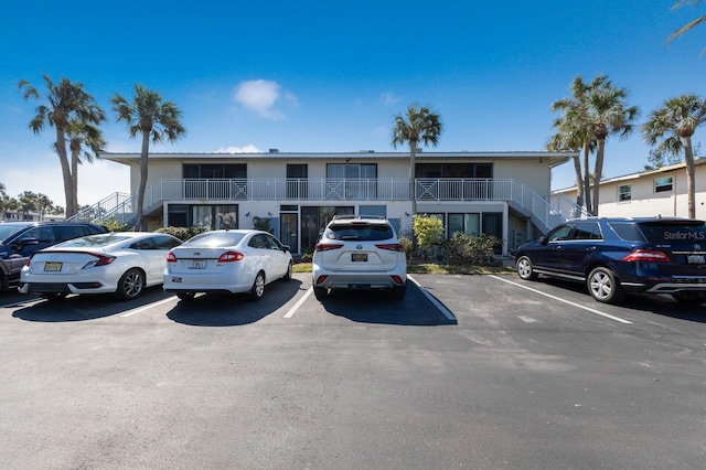 view of property featuring uncovered parking and stairway