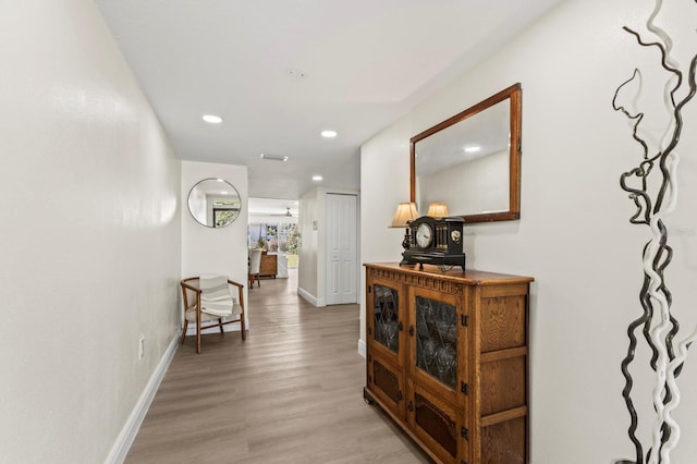 hallway featuring light wood-style flooring, baseboards, and recessed lighting