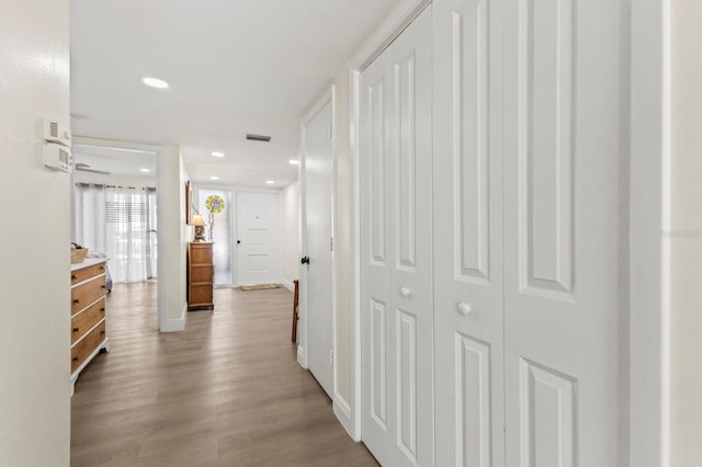 corridor with baseboards, wood finished floors, visible vents, and recessed lighting