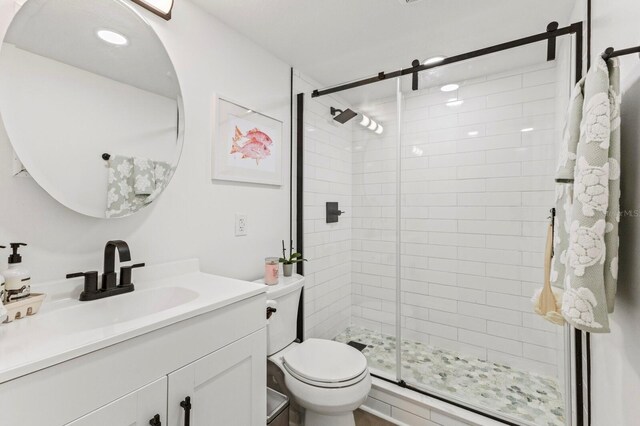 bathroom with a stall shower, vanity, and toilet