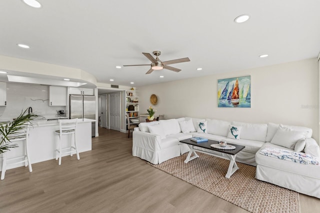 living room featuring light wood-style flooring, visible vents, a ceiling fan, and recessed lighting