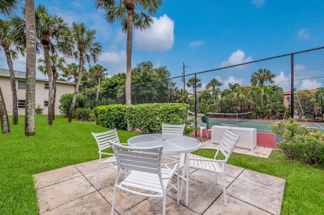 view of patio / terrace with a tennis court, fence, and outdoor dining area