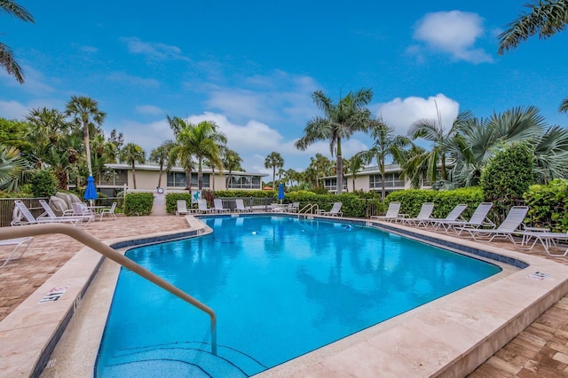 community pool with a patio and fence