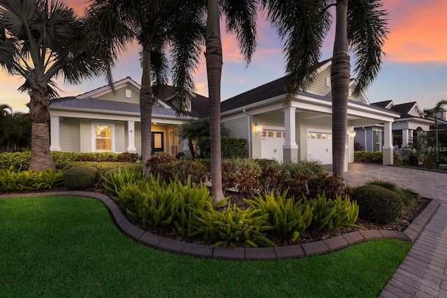 view of front of home with decorative driveway, a front yard, and an attached garage