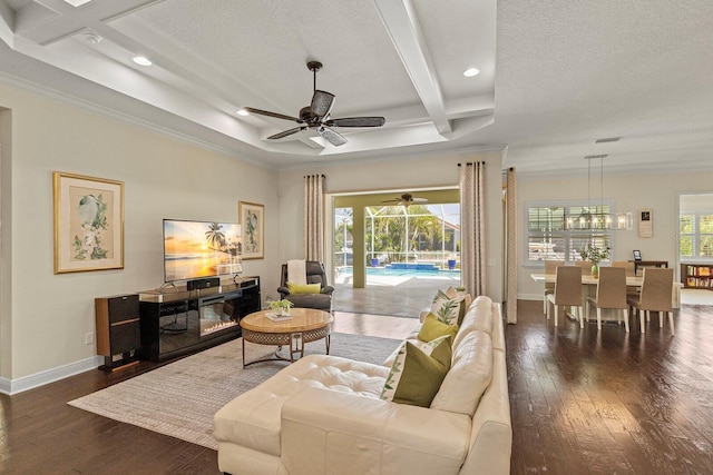 living area featuring a glass covered fireplace, wood-type flooring, plenty of natural light, and baseboards