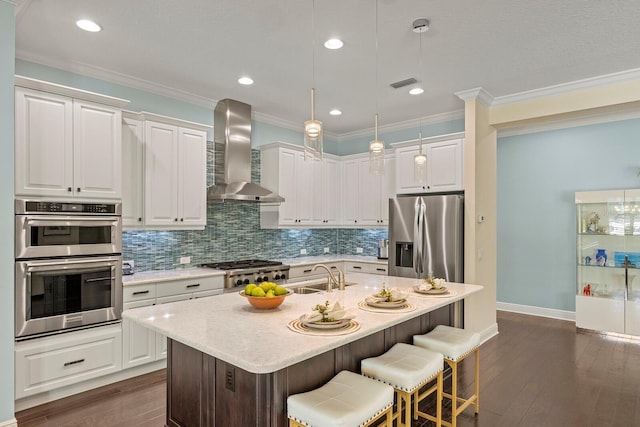 kitchen with ornamental molding, a kitchen breakfast bar, stainless steel appliances, wall chimney range hood, and a sink