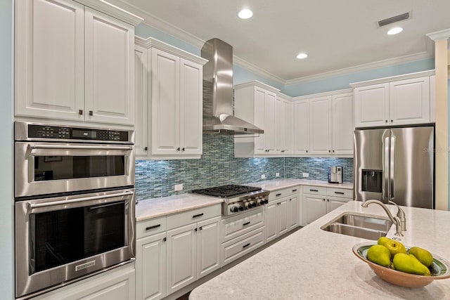 kitchen featuring visible vents, decorative backsplash, wall chimney exhaust hood, stainless steel appliances, and a sink