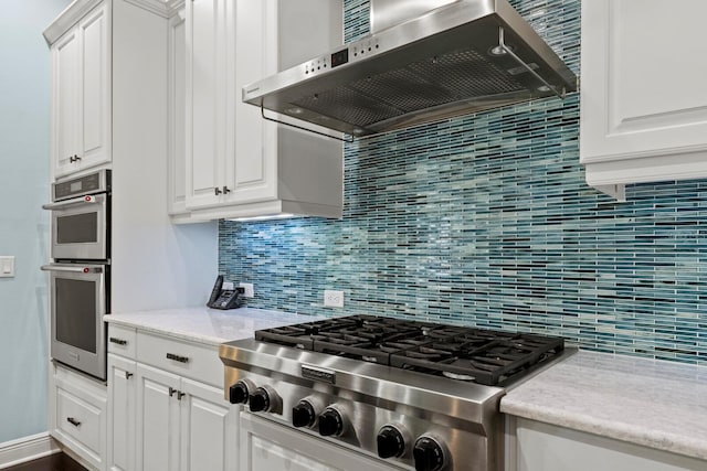 kitchen featuring appliances with stainless steel finishes, range hood, white cabinetry, and decorative backsplash