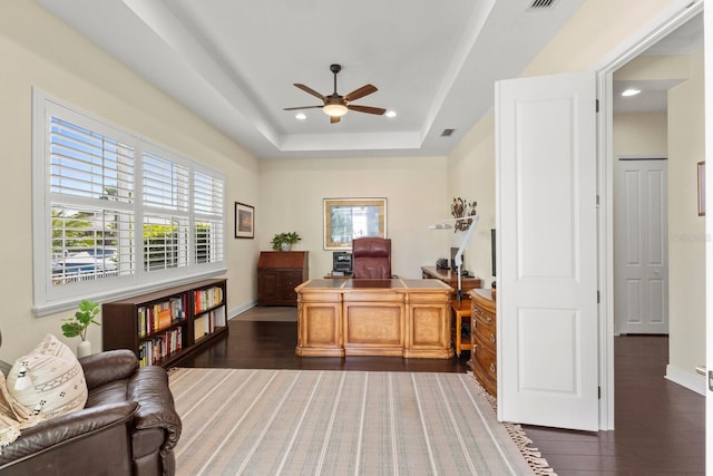 office space featuring a tray ceiling, dark wood-style flooring, and baseboards