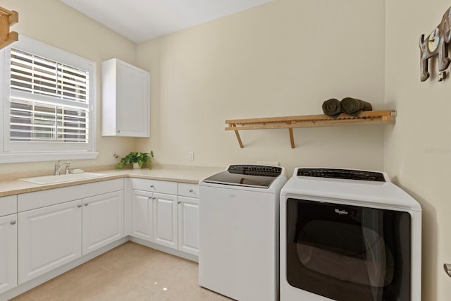 laundry area featuring light tile patterned floors, washer and clothes dryer, a sink, and cabinet space