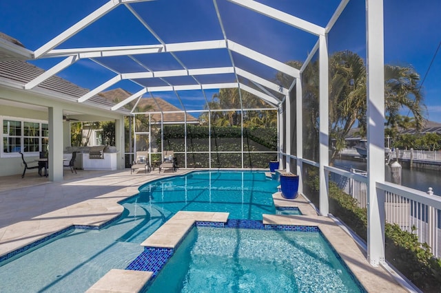 view of swimming pool featuring glass enclosure, a patio area, a pool with connected hot tub, and a ceiling fan