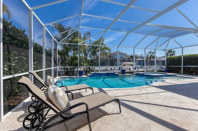 view of pool featuring a patio area, a pool with connected hot tub, and glass enclosure