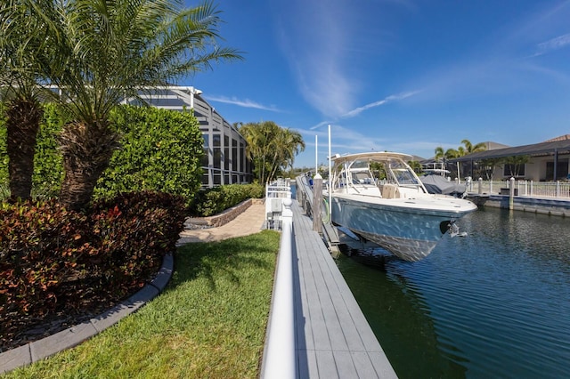 dock area with glass enclosure, a lawn, a water view, and boat lift