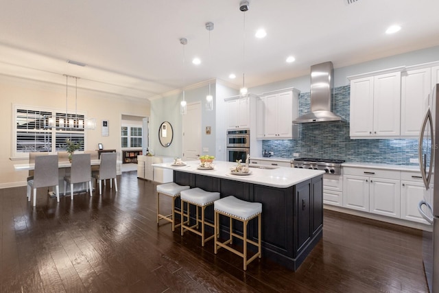 kitchen with stainless steel appliances, a breakfast bar, decorative backsplash, dark wood-style floors, and wall chimney exhaust hood