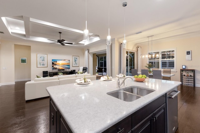 kitchen with a kitchen island with sink, dark wood-type flooring, a sink, open floor plan, and hanging light fixtures