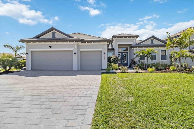 view of front of house with decorative driveway, stucco siding, a front yard, a garage, and a tiled roof