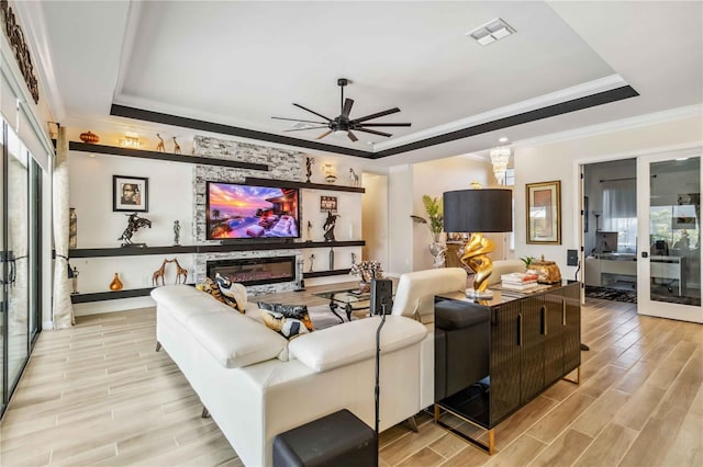 living area featuring plenty of natural light, wood tiled floor, visible vents, and a raised ceiling