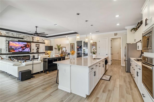 kitchen with light wood finished floors, white cabinetry, appliances with stainless steel finishes, and a sink