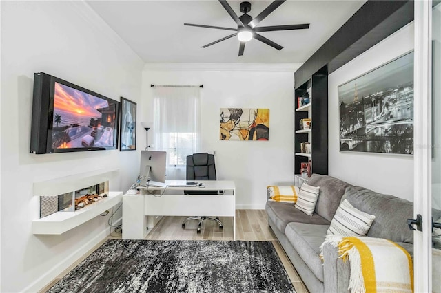 office area with a ceiling fan, ornamental molding, baseboards, and wood finished floors