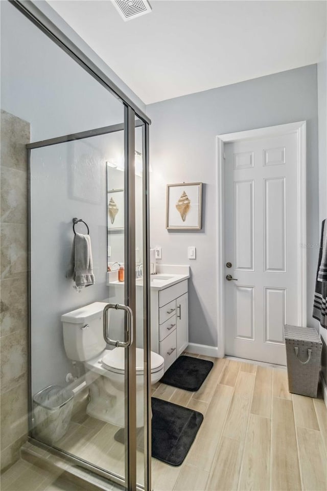 bathroom with visible vents, toilet, a stall shower, wood tiled floor, and vanity