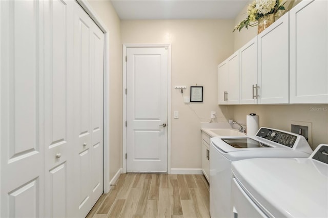 laundry area featuring cabinet space, light wood-style flooring, washing machine and dryer, a sink, and baseboards