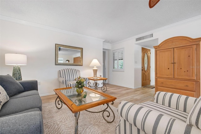 living area with a textured ceiling, ceiling fan, light wood-style flooring, visible vents, and crown molding