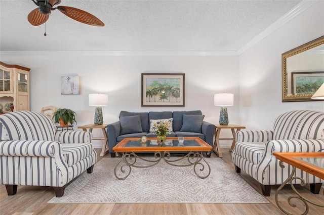 living room with a textured ceiling, ceiling fan, wood finished floors, and crown molding